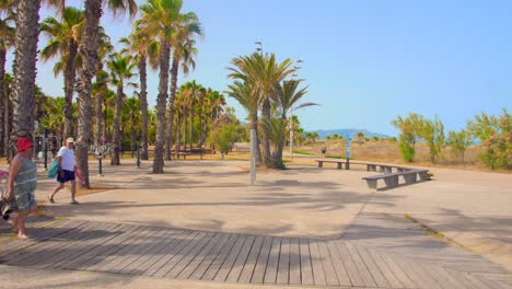 Graues-Gebiet-Mit-Touristen,-Die-Auf-Dem-Holzsteg-Spazieren-Gehen,-Der-Zum-Pinar-strand-In-Castellon,-Spanien-Führt---Breiter-Schuss