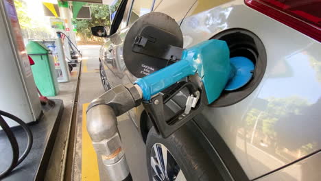 Close-up-shot-of-a-gas-pump-nozzle-filling-up-an-SUV-at-a-gas-station