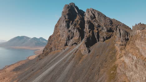 Großer-Berg-Mit-Einem-Orangefarbenen-Leuchtturm-Im-Vordergrund