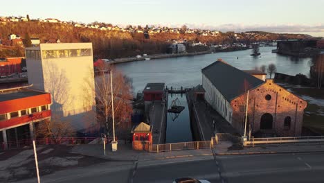 Skien-sluice-in-Telemark-channel-Norway---Sunset-evening-aerial-flying-above-sluice-with-people-taking-evening-walk-on-bridge-in-beginning-of-clip