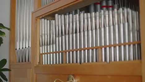 Silver-pipes-of-a-home-organ-with-a-wooden-frame-in-a-recording-studio