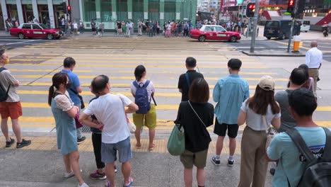 Asiatische-Fußgänger-Und-Pendler-Warten-Am-Bürgersteig,-Bis-Ein-Ampelsignal-Auf-Grün-Schaltet,-Bevor-Sie-über-Eine-Hektische-Und-Belebte-Zebraüberquerungskreuzung-Eilen-Und-Gehen