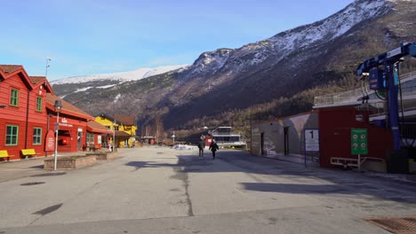 Flam-village-and-tourist-destination---Panning-right-from-buildings-to-reveal-electric-passenger-boat-Future-of-the-fjords-in-the-harbor---Blue-sky-and-mountain-background
