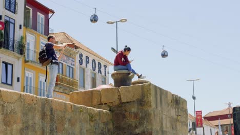 Tourist-taking-pictures-of-Porto-with-Cable-Cars-passing-above,-Portugal-4K-SLOWMO-CINEMATIC-SUMMER-MEDITERRANEAN-CITY