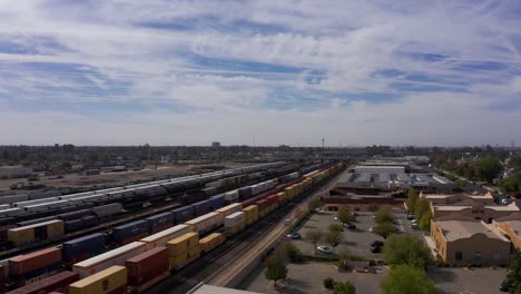 Toma-Aérea-Baja-Después-De-Un-Tren-De-Carga-Que-Pasa-Por-Los-Ferrocarriles-Del-Centro-De-Bakersfield,-California