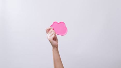 Woman's-hand-shows-a-cloud-icon-color-pink-symbol-in-white-studio-background-with-copy-space