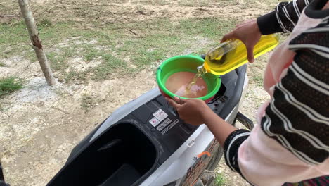 Balinesische-Frauen-Füllen-Roller-Mit-Benzin,-Indem-Sie-Es-Aus-Der-Flasche-In-Lombok-Gießen