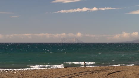 Man-walking-dog-next-to-ocean-during-cloudy-morning