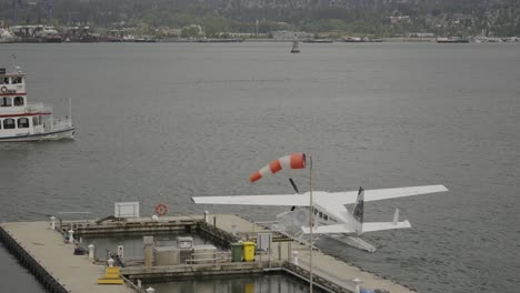 Vista-De-Un-Ferry-Navegando-En-El-Mar-De-La-Bahía-De-Vancouver-Cerca-Del-Hidroavión-Atracado-En-El-Muelle-Del-Centro-De-Vuelo-Del-Puerto,-Columbia-Británica,-Canadá