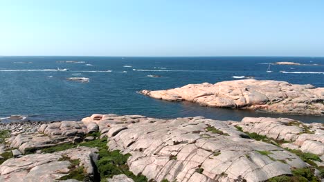 Boats-Cruising-Across-The-Blue-Sea-Viewed-From-Rocky-Coast-Of-Bohuslan-With-Granite-In-Gotaland,-Sweden