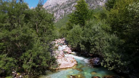 Agua-Cristalina-Del-Arroyo-Que-Fluye-A-Través-De-árboles-Y-Rocas-En-Hermosas-Montañas-Alpinas-Altas-En-Albania