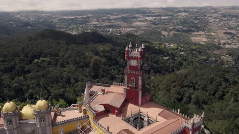 Brightly-coloured-red-and-yellow-towers-of-Pena-Palace,-Sintra,-against-Natural-Park-forest