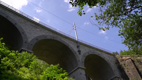 Looking-up-at-Viaduct-arches-against-blue-sky-with-train-tracks