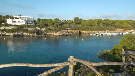 Swimmers-practicing-at-dawn-in-Cala-Santandra-cove-in-Menorca,-Spain