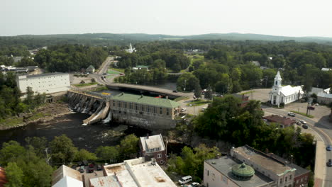 Aerial-footage-of-Skowhegan,-Maine-Island-downtown-with-Kennebec-River-Hydroelectric-Dam-and-church-in-the-foreground