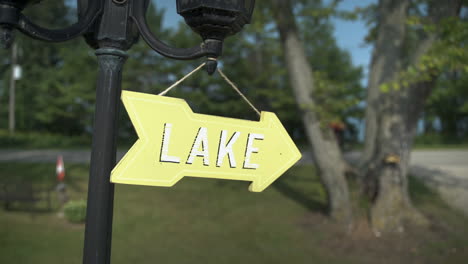 Pan-to-reveal-yellow-sign-pointing-to-the-lake-as-cyclist-rides-by