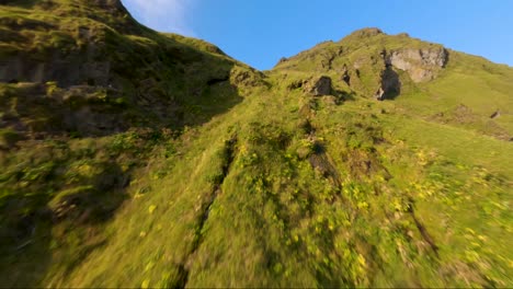 Drone-flying-to-the-top-of-a-hill-near-Vik,-Iceland
