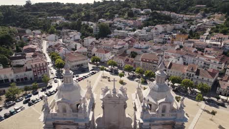 Fly-over-two-striking-church-towers,-Alcobaça-Monastery,-Portugal