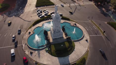 Luftbahnaufnahme-Der-Berühmten-Carta-Magna-Statue-Und-Sprühbrunnen-Mit-Fahrenden-Autos-Während-Des-Sonnenuntergangs-In-Buenos-Aires
