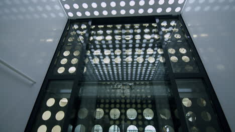 Slowmotion-low-angle-shot-of-inside-elevator-with-circles-pattern-going-dwon