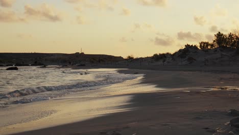slow-motion-sandy-beach-shoreline-of-relaxing-evening-sunset-hour,-small-waves-crashing