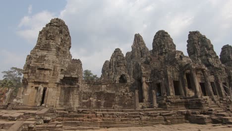 Ancient-structure-the-mystical-Bayon-khmer-temple,-Angkor-Thom,-Cambodia,-handheld-pan-shot