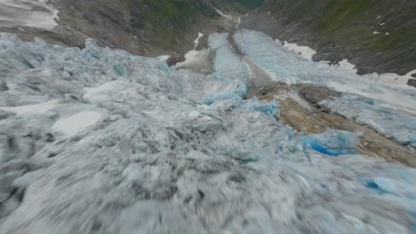 Dynamic-fpv-flight-over-melting-glacier-ice-in-Norwegian-Mountains---Buarbreen,Norway