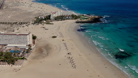 Drone-dolly-in-shot-over-the-hotel-complex-overlooking-the-beach-of-Corralejo,-Fuerteventura,-Canary-Islands