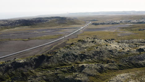 Road-traveling-through-beautiful-icelandic-mountain-landscape,-aerial