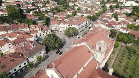 Aerial-pan-shot-overlooking-at-the-traffic-on-Avenida-25-de-Abril,-parish-townscape-and-Arouca-Abbey