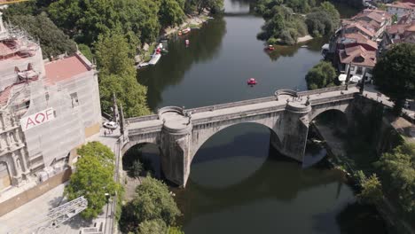 Historical-stone-bridge-over-river-with-cityscape-view-of-Amarante-town,-aerial-orbit-view