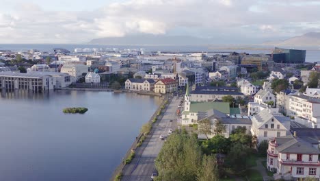 Downtown-Iceland-with-lake-Tjörnin-during-scenic-golden-hour-sunset,-aerial
