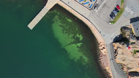 Flying-Over-Calm-Green-Waters-Of-Sea-Near-Harbour-Towards-Havets-Hus-Aquarium-In-Lysekil,-Bohuslan,-Sweden