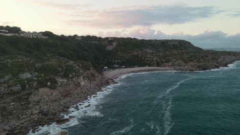 4K-Drone-footage-facing-a-little-beach,-with-a-beautiful-sunset-on-the-island-of-Portland,-in-Dorset