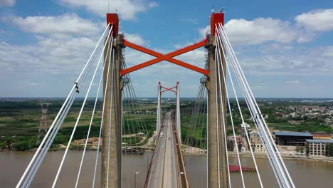 Drone-flying-backwards-revealing-the-amazing-huge-bridge-of-Zarate-where-vehicles-are-crossing-it,-Argentina
