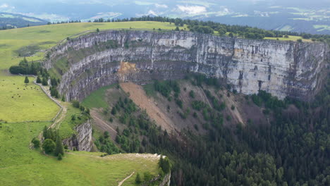 Wide-drone-shot-of-Creux-du-Van-in-Switzerland,-located-at-the-border-of-the-cantons-of-Neuenburg-and-Vaud