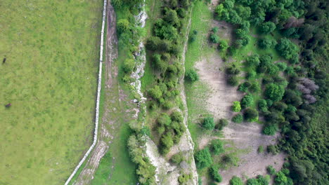 Downward-angle-drone-shot-of-Creux-du-Van-in-Switzerland,-located-at-the-border-of-the-cantons-of-Neuenburg-and-Vaud