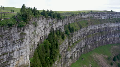 Cinematic-drone-shot-of-Creux-du-Van-in-Switzerland,-located-at-the-border-of-the-cantons-of-Neuenburg-and-Vaud