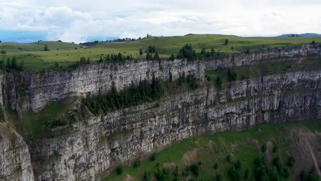Drone-shot-of-cliff-walls-at-Creux-du-Van-in-Switzerland,-located-at-the-border-of-the-cantons-of-Neuenburg-and-Vaud
