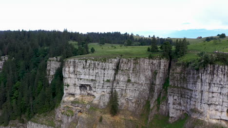 Rotating-drone-shot-of-the-cliff-walls-at-Creux-du-Van-in-Switzerland,-located-at-the-border-of-the-cantons-of-Neuenburg-and-Vaud