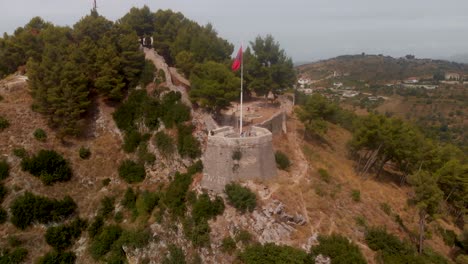 Drone-Aéreo-Lento-Sobre-La-Hermosa-Torre-De-Vigilancia-Con-Bandera-Albanesa-En-Berat