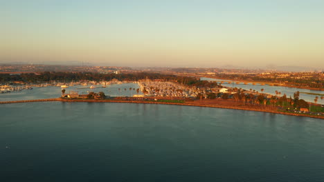 Beautiful-aerial-scenery-of-Mission-Bay-with-blue-water-and-warm-orange-sunset-sky,-drone-view
