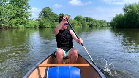 Muscular-man-paddling-canoe-on-river-wye-in-black-top-on-sunny-day