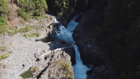 Narrow-passage-between-rocky-canyon-with-flowing-water-rapids,-Waikato