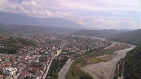 High-above-view-over-town-next-to-river-with-mountains-in-background