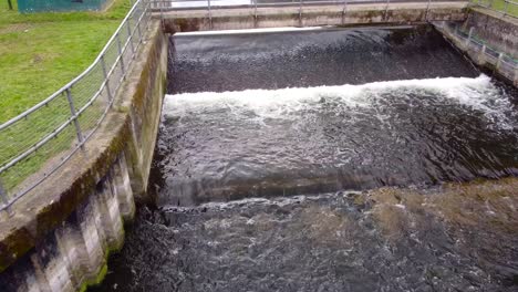Aerial-approach-to-the-small-water-dam-on-the-Little-Ouse-river-near-Thetford-in-the-UK