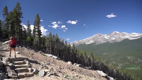 Wanderin-Mit-Rucksack-Auf-Wanderweg,-Atemberaubender-Blick-Auf-Rocky-Mountains-An-Sonnigen-Sommertagen,-Colorado-USA,-Rückansicht,-Vollbild,-Zeitlupe