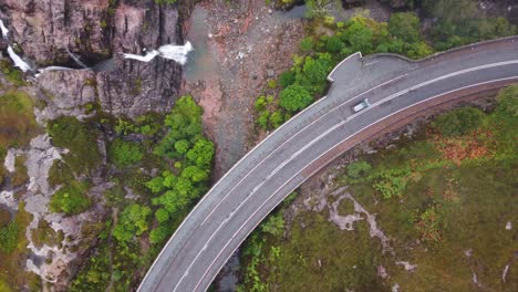 Car-Driving-A82-at-Glencoe-Waterfall,-The-Meeting-of-Three-Waters,-Scottish-Highlands,-Scotland---Aerial-Drone-4K-HD-Footage,-Top-Down,-Zoom-Down