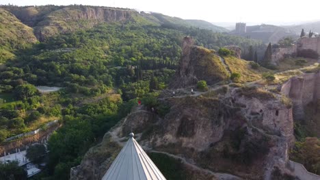 Filmische-Drohnenaufnahme,-Die-Hügel-Zeigt-Und-An-Sonnigen-Tagen-In-Tiflis-Eine-Wunderschöne-Gelbe-Kirche-Enthüllt