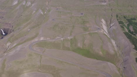 Meandering-gravel-road-going-up-steep-mountain-in-Iceland,-aerial